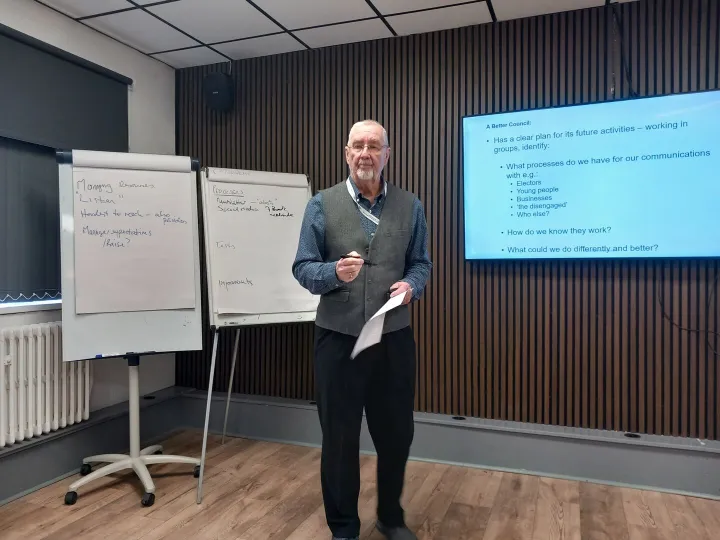 A trainer standing beside flip charts and a presentation screen