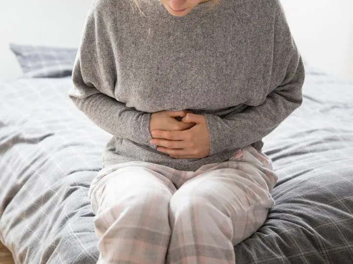 Sick woman with hands on stomach suffering from