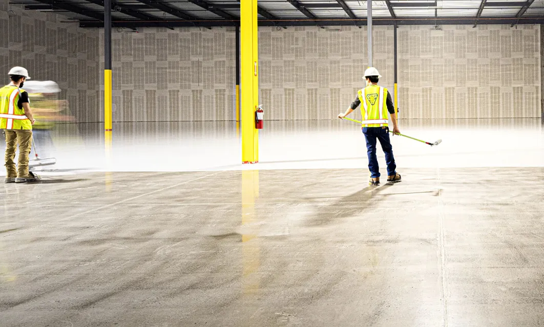 Two workers sweeping a warehouse floor