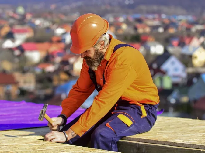 Roofer worker in special protective work wear new roof under