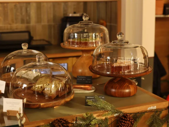 Showcase of pastries and cakes under glass domes on wooden s