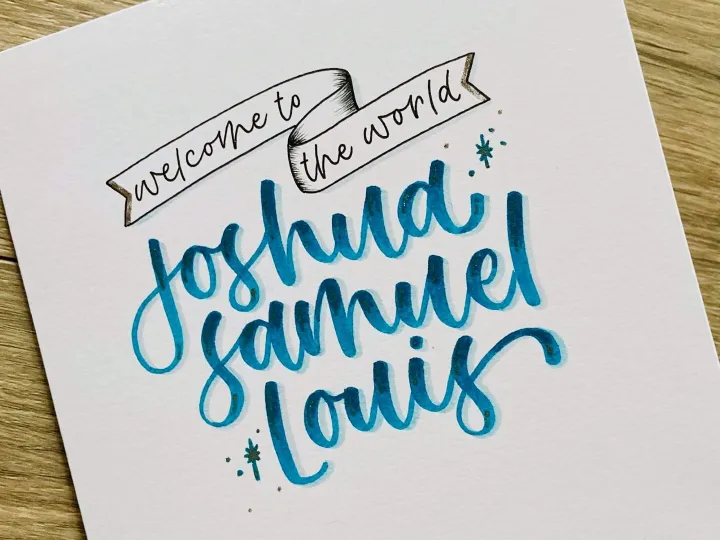 Teal brush lettered name card reading Joshua Samuel on textured paper