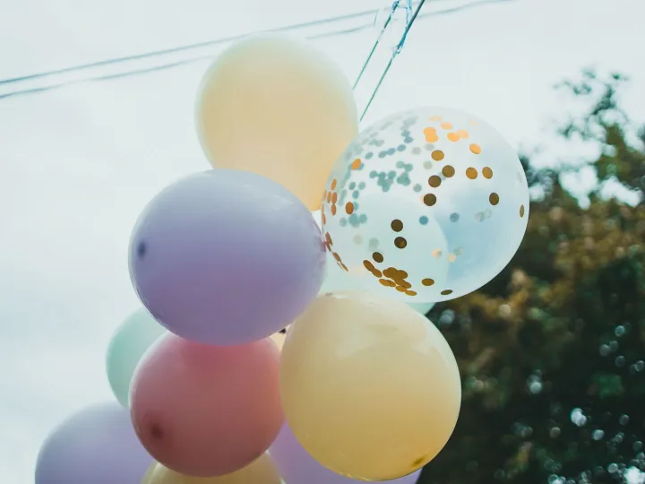 A cluster of pastel helium balloons tied with ribbon