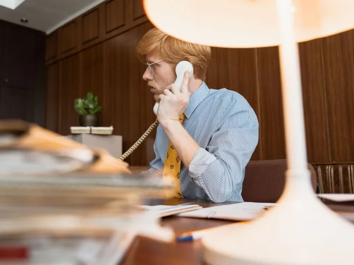 A man taking a call on an old telephone in a small office