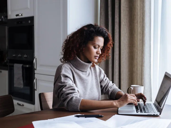 A council clerk working on a laptop at a kitchen table with paperwork