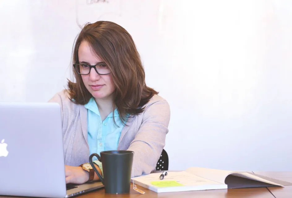 A woman checking email on a laptop at her desk