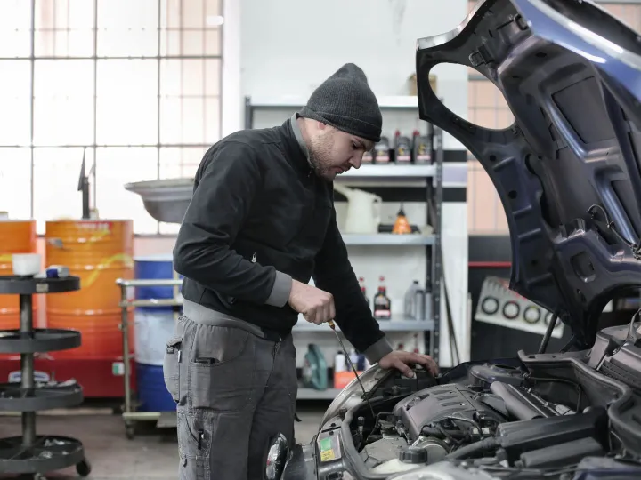 Mechanic checking a car engine in a garage workshop