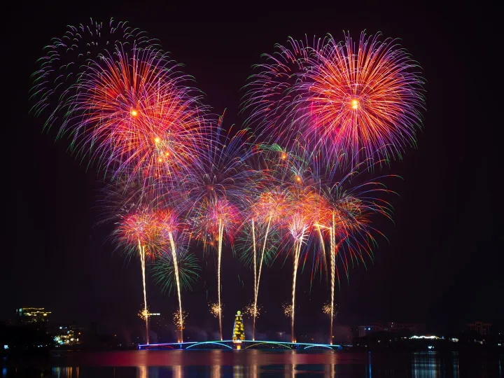 Vivid fireworks burst over a peaceful water