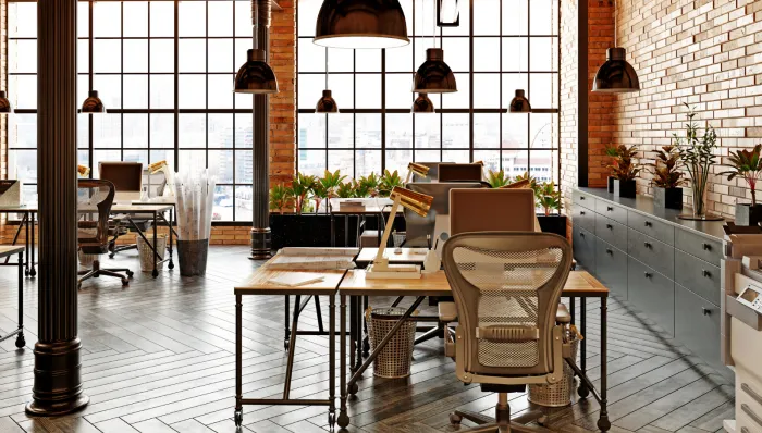 Open plan office with large windows and brick wall