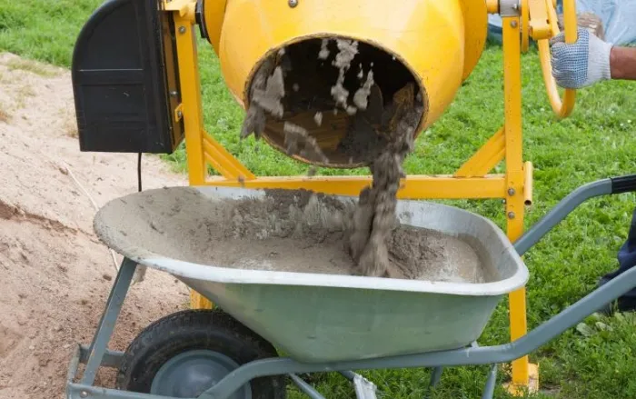 Worker fills cement concrete mixer