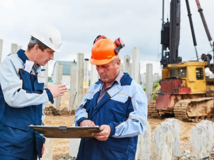 Construction workers in front of pile driver machine