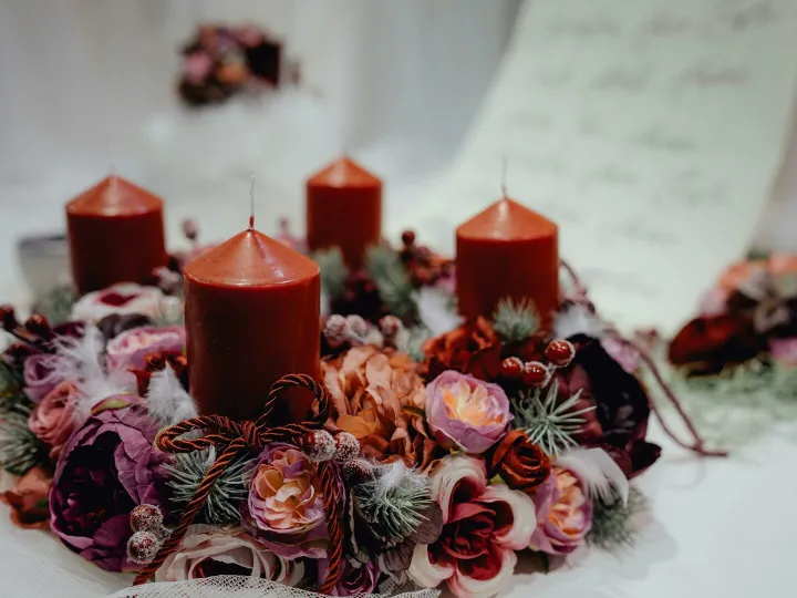 Warm, festive candle wreath adorned with floral decorations, perfect for Christmas table settings.