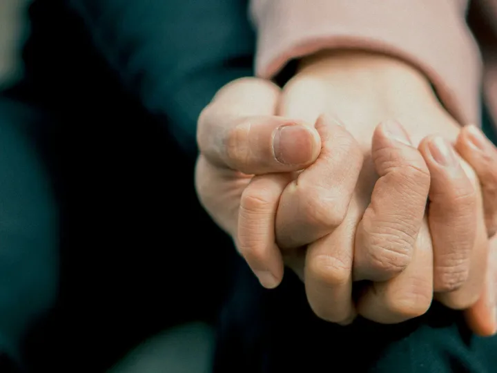 A close-up photo capturing two adult hands holding each other, symbolizing love and support.