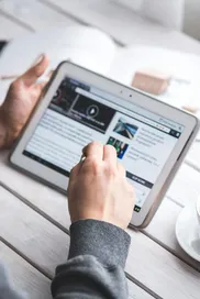 A man uses a tablet to browse news while enjoying