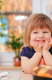 A happy young girl smiling indoors surrounded by