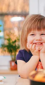 A happy young girl smiling indoors surrounded by
