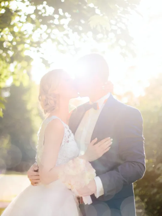 bride-and-groom-kissing-near-tree-against-the-sun-photo-1244700