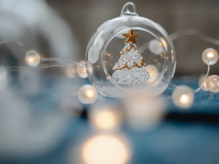 Glass Christmas tree inside transparent ball surrounded by burning garland for festive decorations
