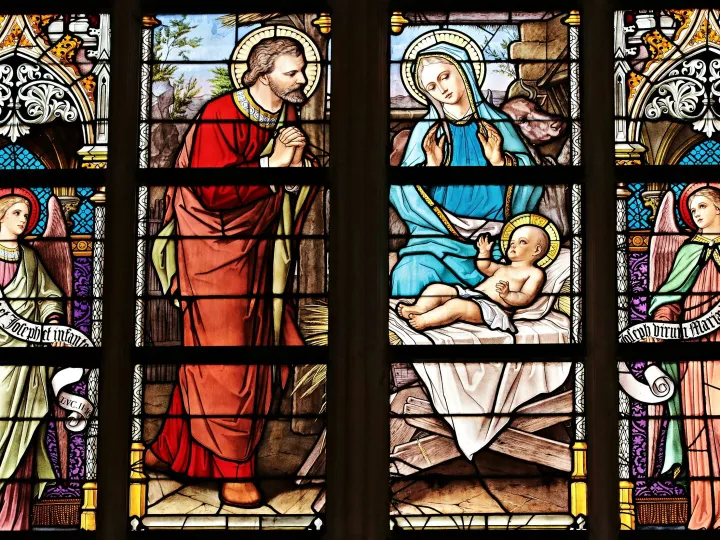 Vibrant stained glass window illustrating a biblical nativity scene with vivid colors in a church setting.