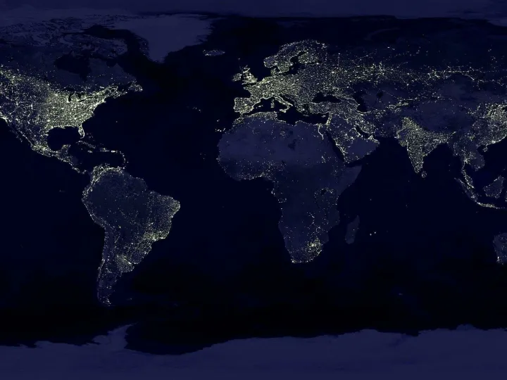 Satellite view of Earth at night with illuminated cities across continents.