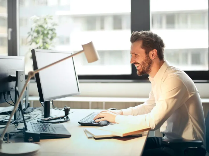 A man smiling while working at an office desk with