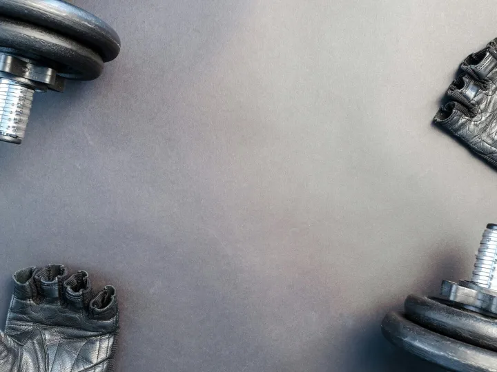 Flat lay of dumbbells and gloves on a workout surf