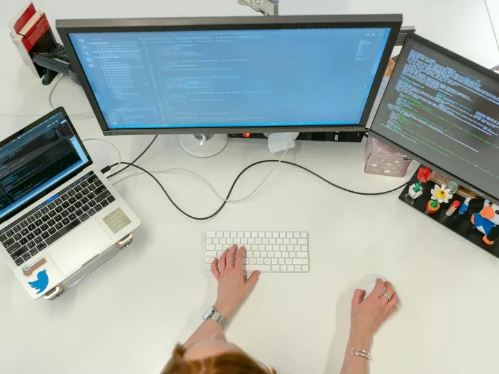 A female software engineer coding on dual monitors