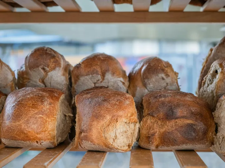 Close-up of rustic, crusty loaf bread displayed on a wooden shelf.
