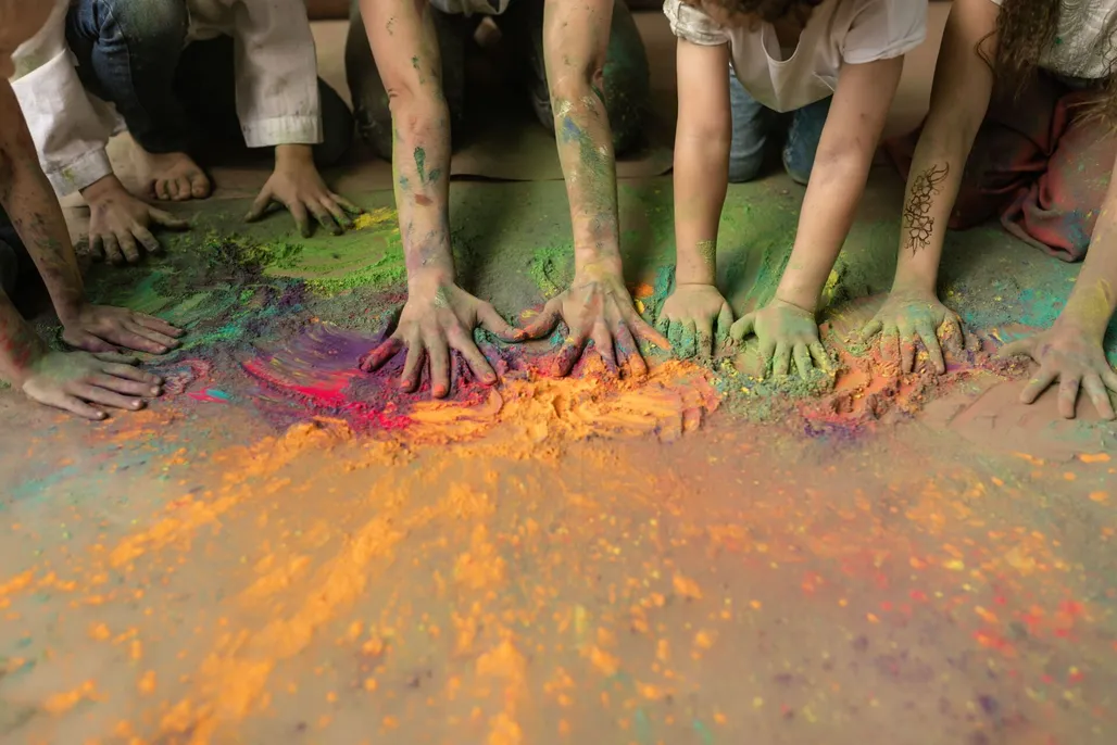 Children's hands mixing brightly coloured craft powder at Messy Church