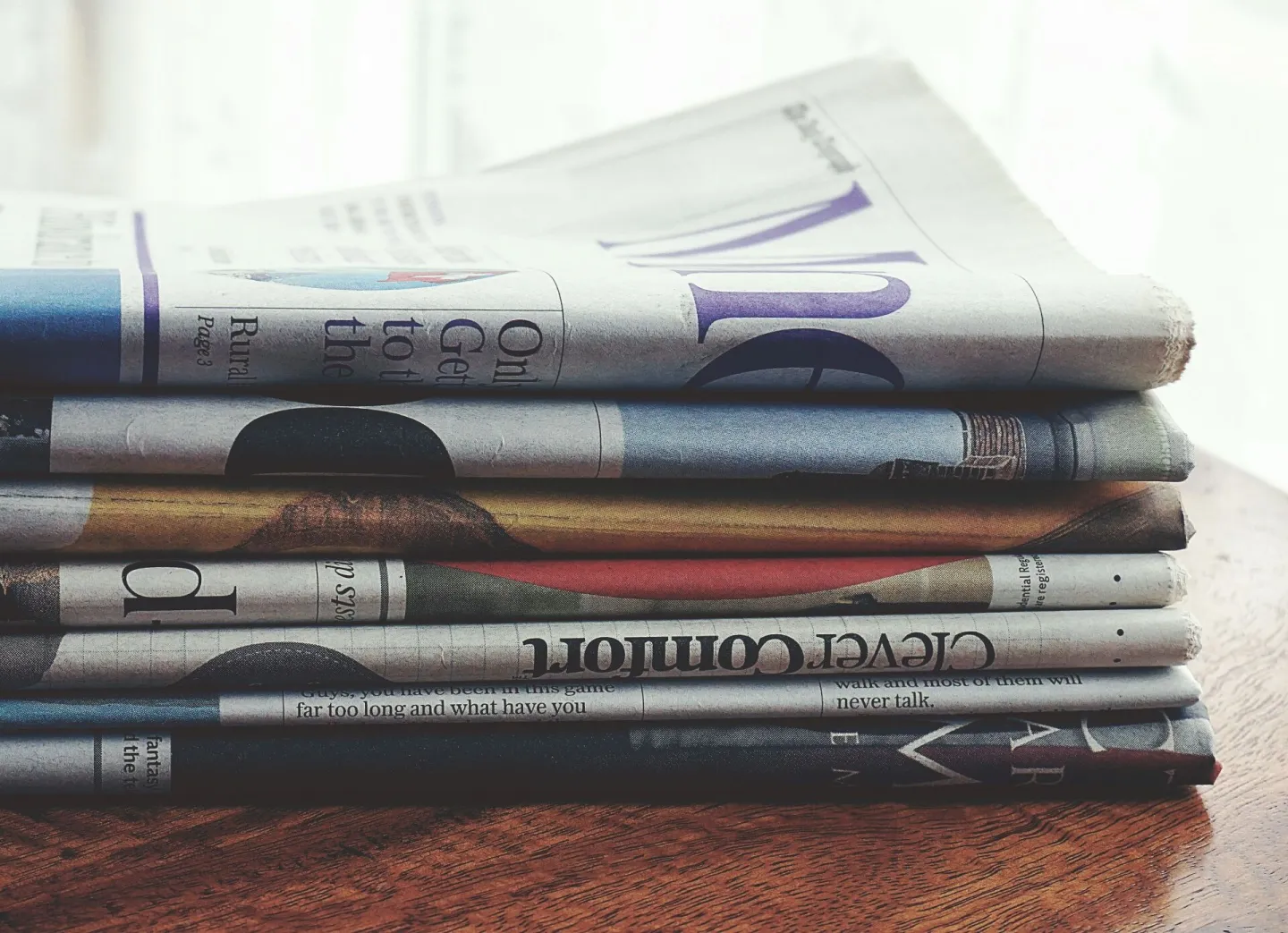 A stack of folded newspapers placed on a wooden