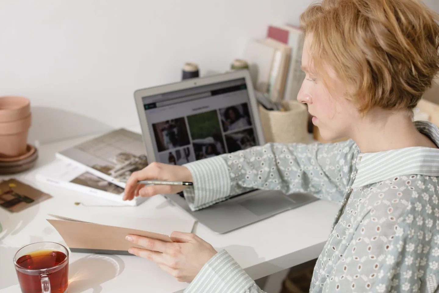 Church administrator working at a laptop with a notebook and a cup of tea