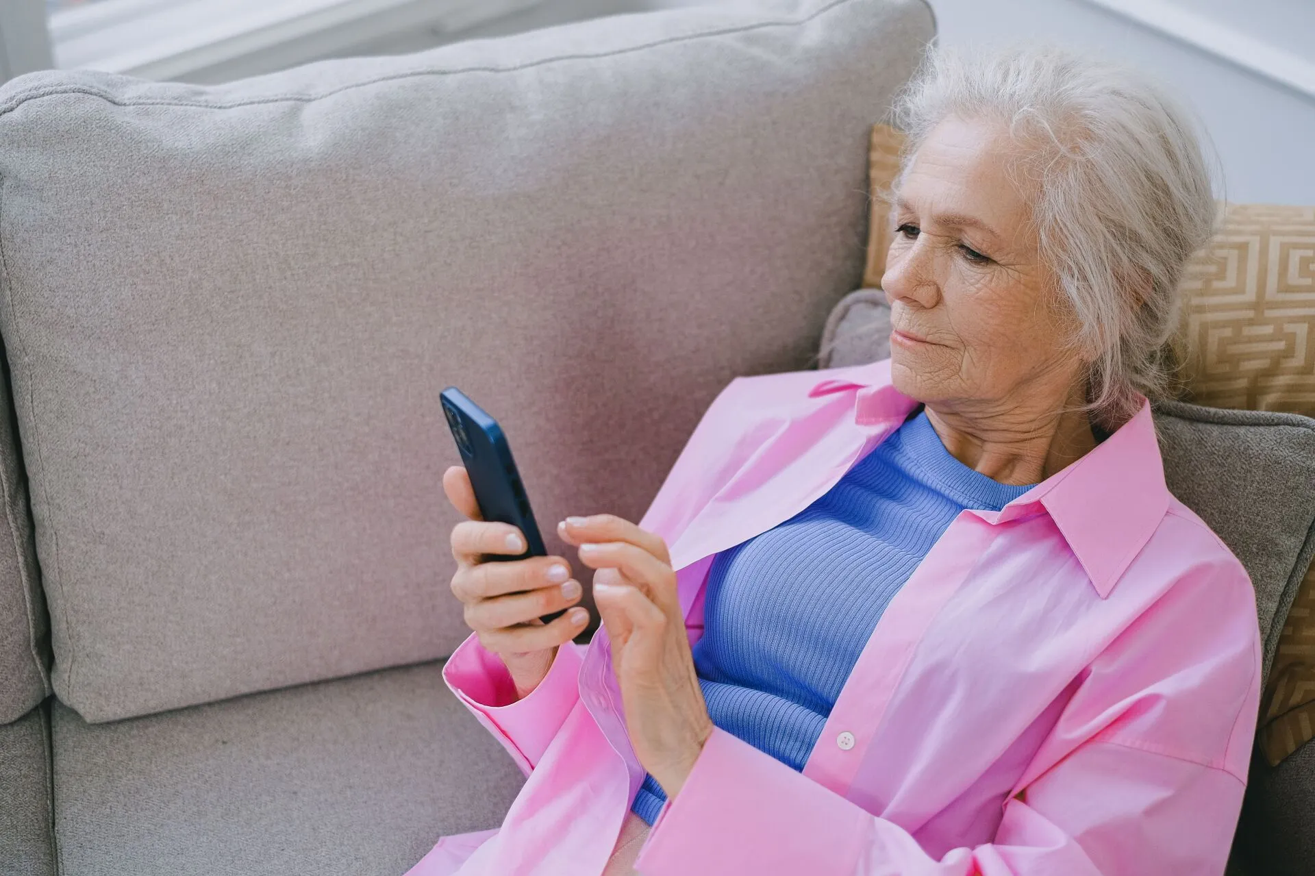 Older woman reading church news on her smartphone at home