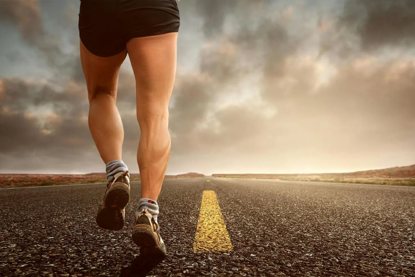 Runner's legs on a road during a sunset