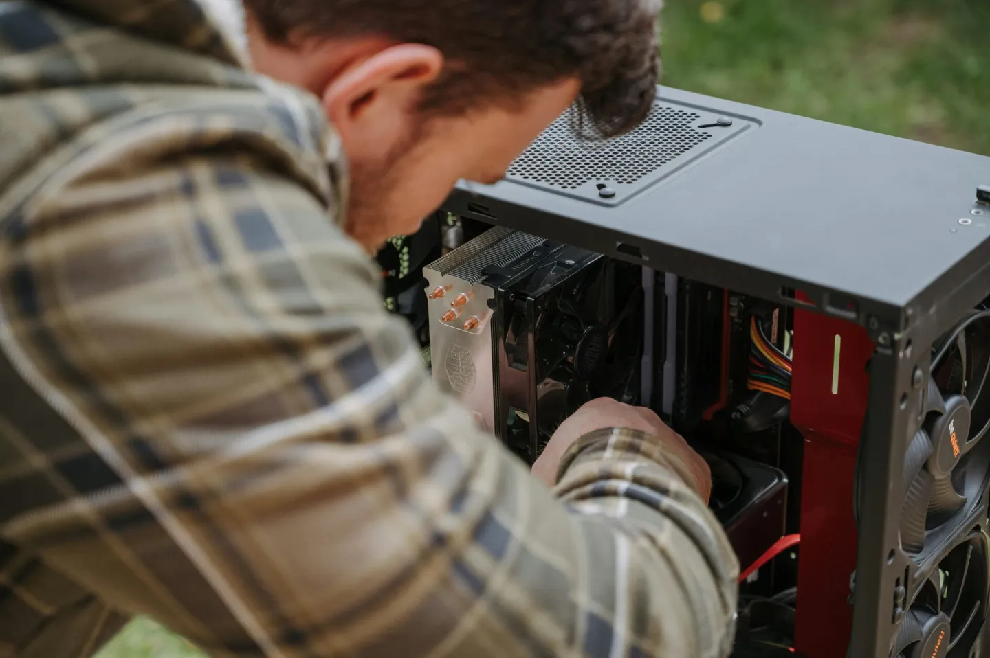 A man cleans and maintains a desktop PC outdoors