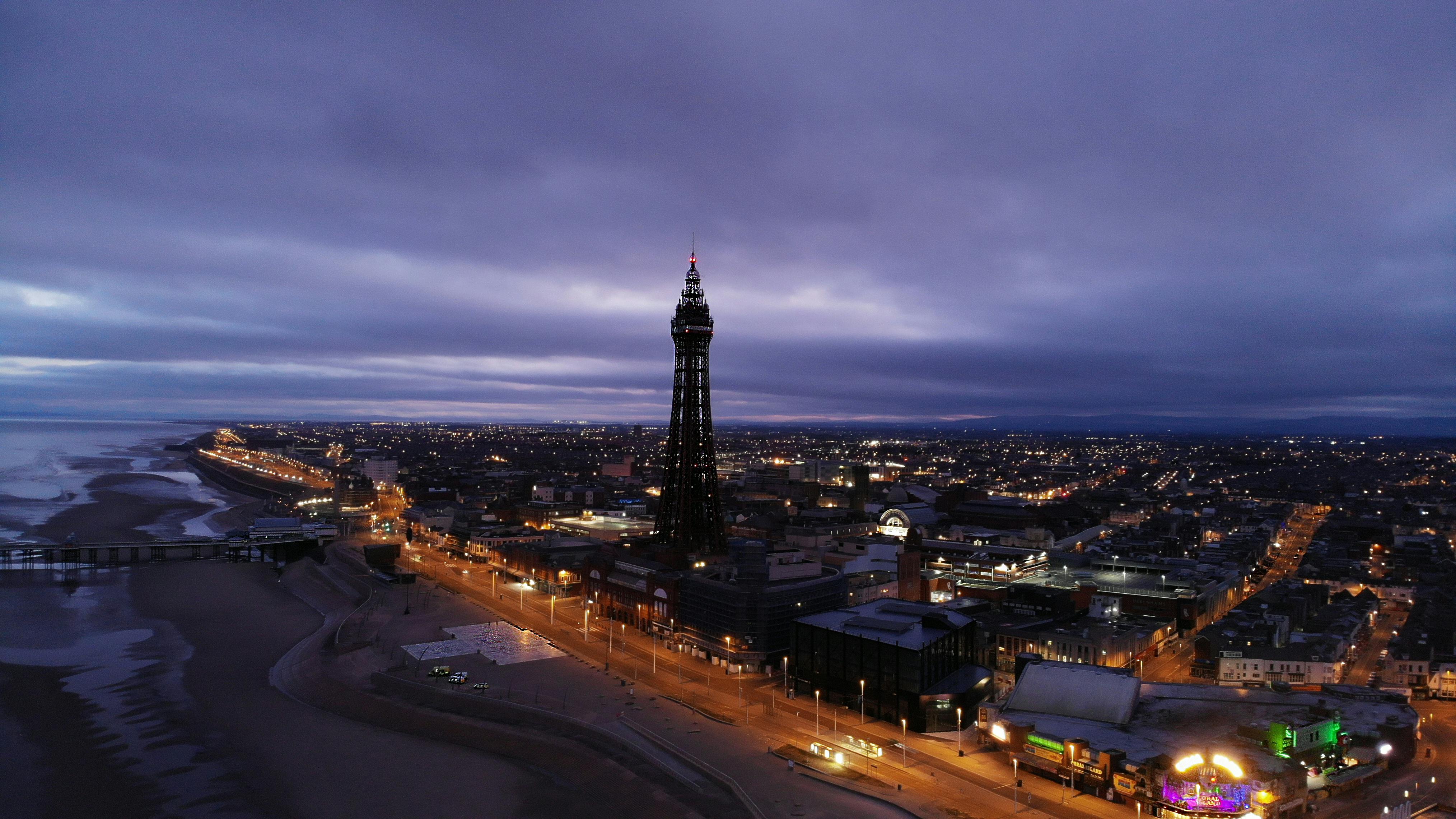 Drone view of Blackpool Tower and cityscape at dusk, capturing urban lights and coastline