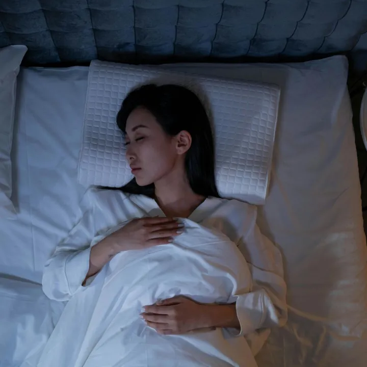 Calm and peaceful woman resting in bed under dim