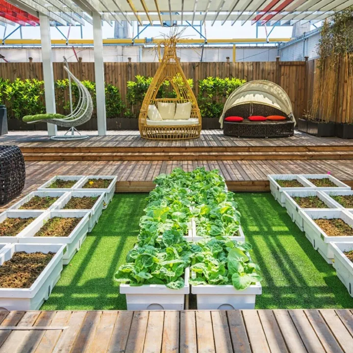Garden with artificial grass, white raised vegetable beds and a timber deck with seating