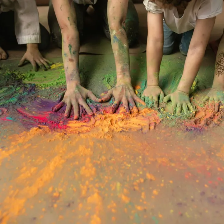Children's hands mixing brightly coloured craft powder at Messy Church
