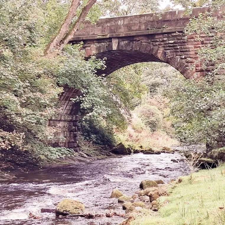 The River Dane flowing under an old stone bridge near Wincle
