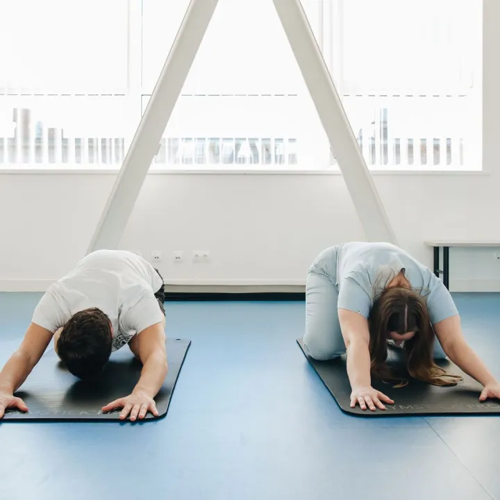 Two people exercising on mats in a modern studio