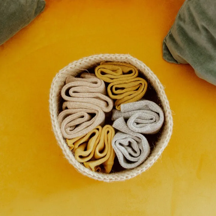 Neatly rolled socks in a woven basket