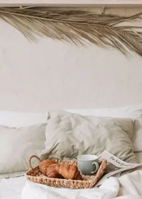 A breakfast tray with croissants and coffee on a freshly made bed