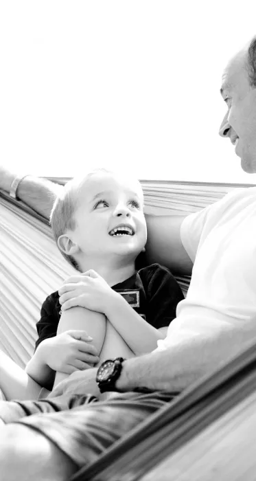 Grayscale Photo of Man and Child Sitting on Hammock