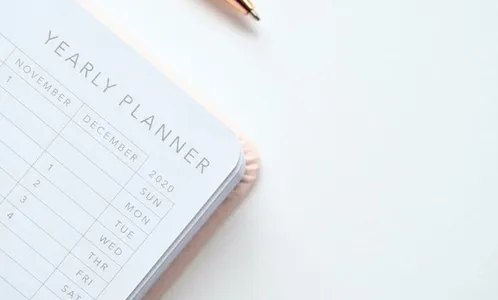 Close-Up Photo of Yearly Planner Beside a Pen 