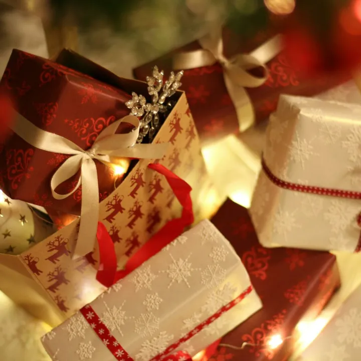 Beautifully wrapped Christmas presents under the tree with festive decorations and ribbons.