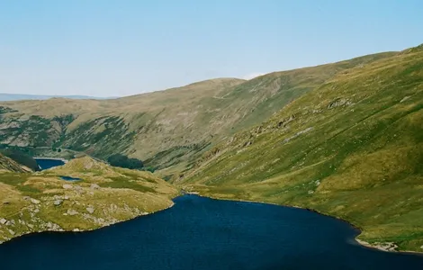 Aerial view of a tranquil lake surrounded by rolling hills in England's Lake District.