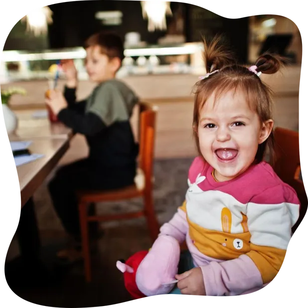 Funny baby girl sitting in cafe and laughs