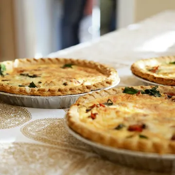 Delightful homemade quiches on a classic patterned tablecloth, inviting and delicious.