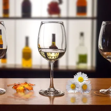 Wine glasses on a table with daisies
