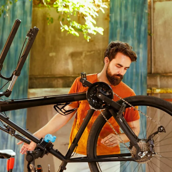 Athletic male repairs modern bicycle